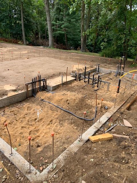 Concrete foundation forms with rebar stakes at a wooded construction site