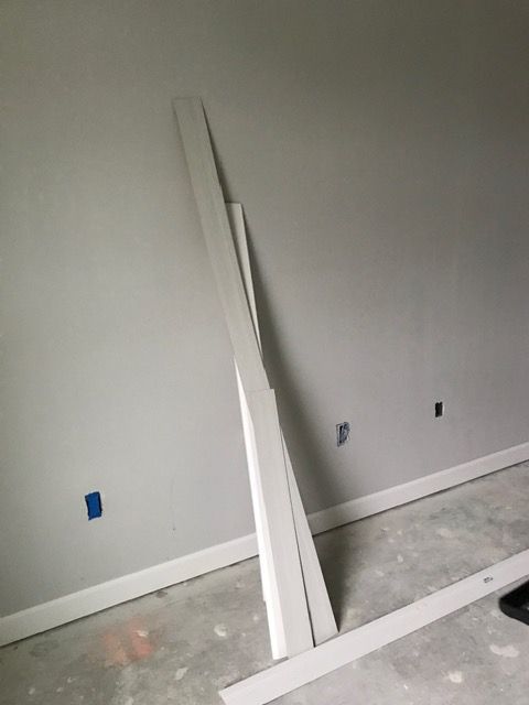 White trim boards leaning against a gray wall in a room under construction
