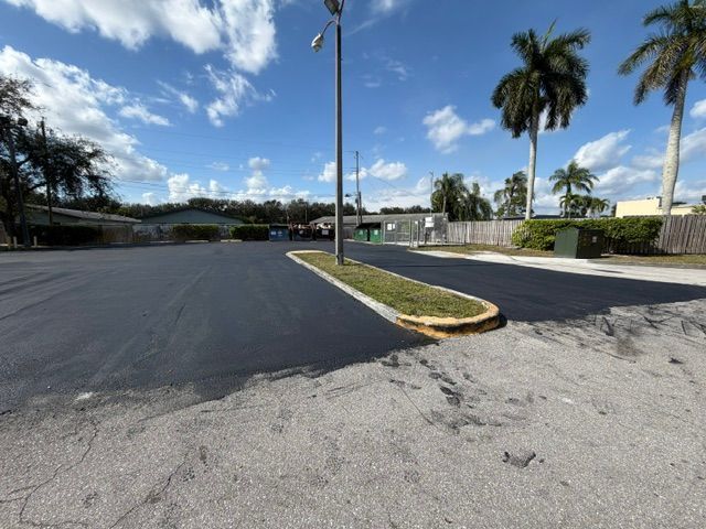 Empty paved road with curb and palm trees under a blue sky on a sunny day
