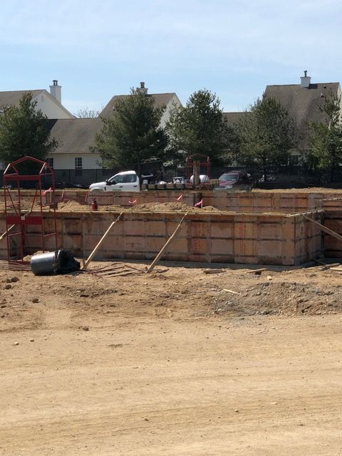 Construction site with large wooden foundation forms and a dump truck in a dusty neighborhood area