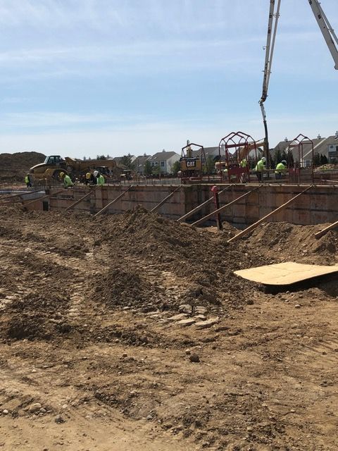 Construction site with workers, excavator, and dirt trench under a clear sky
