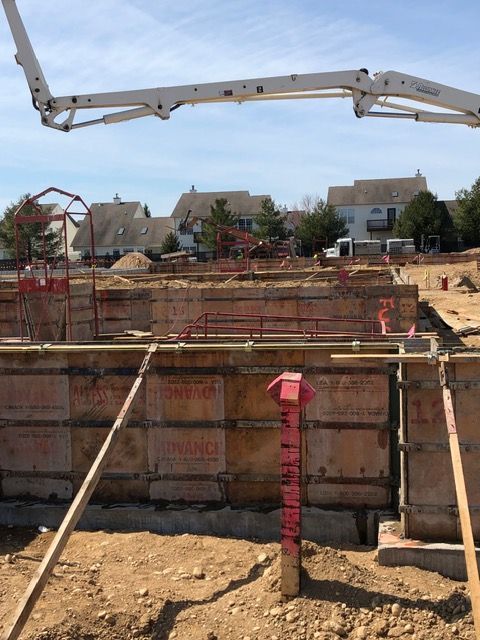Concrete foundation forms at a residential construction site with a pump boom overhead