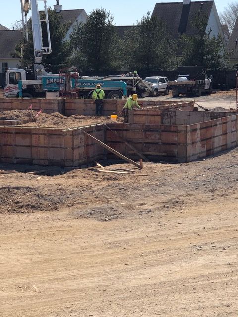 Construction workers on a dirt worksite beside a large circular foundation and machinery.
