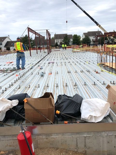 Construction site with workers on rebar-covered concrete slab and a crane in the background