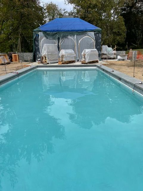 Swimming pool with clear blue water and a blue-and-white cabana in the background