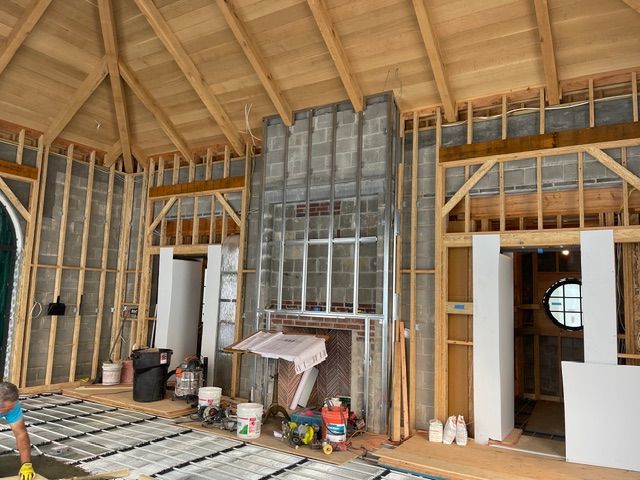 Unfinished room with exposed framing, open windows, tools, and construction supplies on the floor.