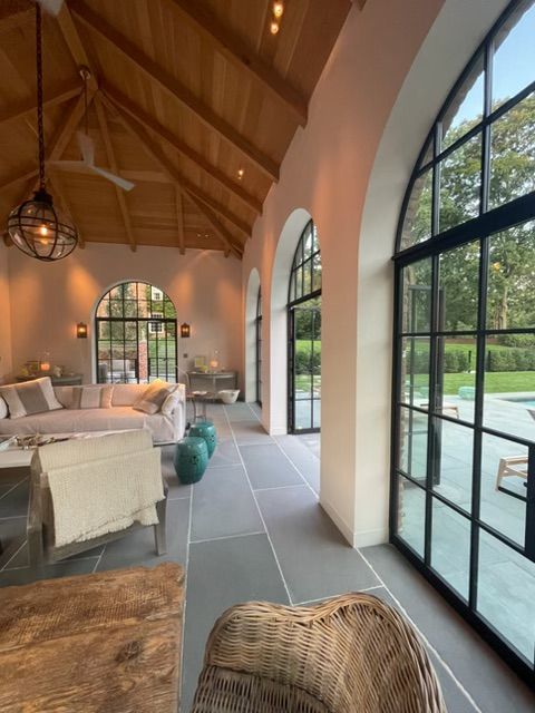 Sunlit living room with vaulted wood ceiling, arched windows, and a view of the lawn