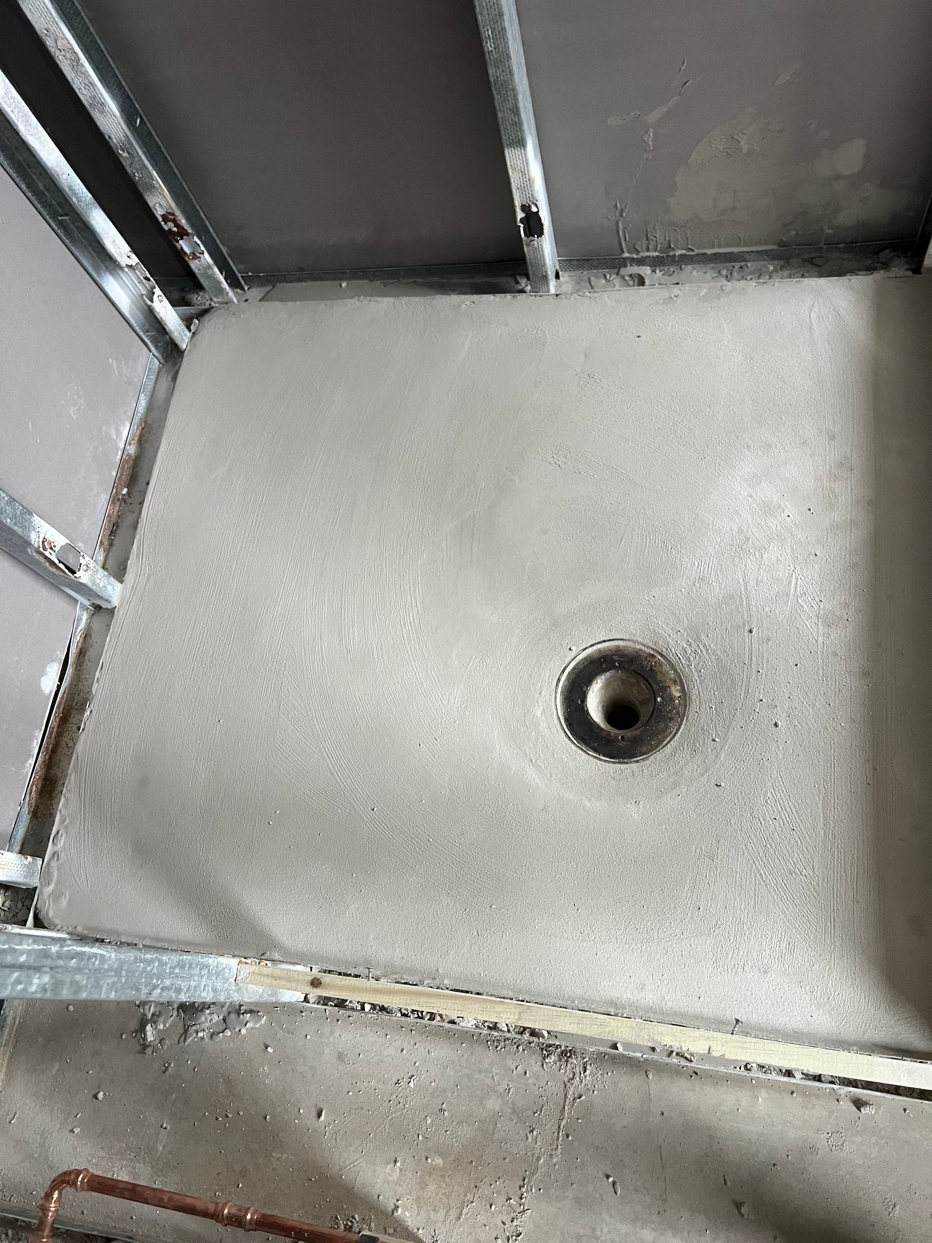 Empty gray shower floor with a central drain and tiled walls.