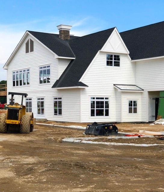 A large white house with a black roof is under construction