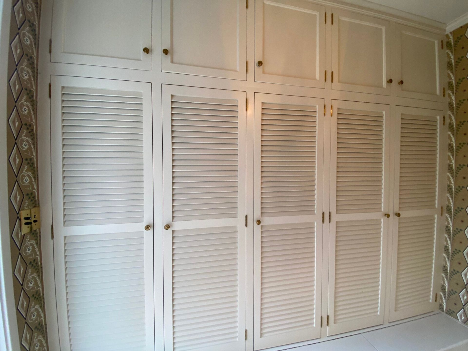 A room with lots of white cabinets and shutters