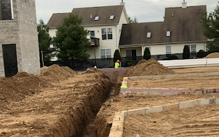 A construction site with a large house in the background.