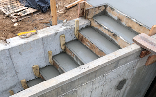 A concrete staircase is being built into a concrete wall.