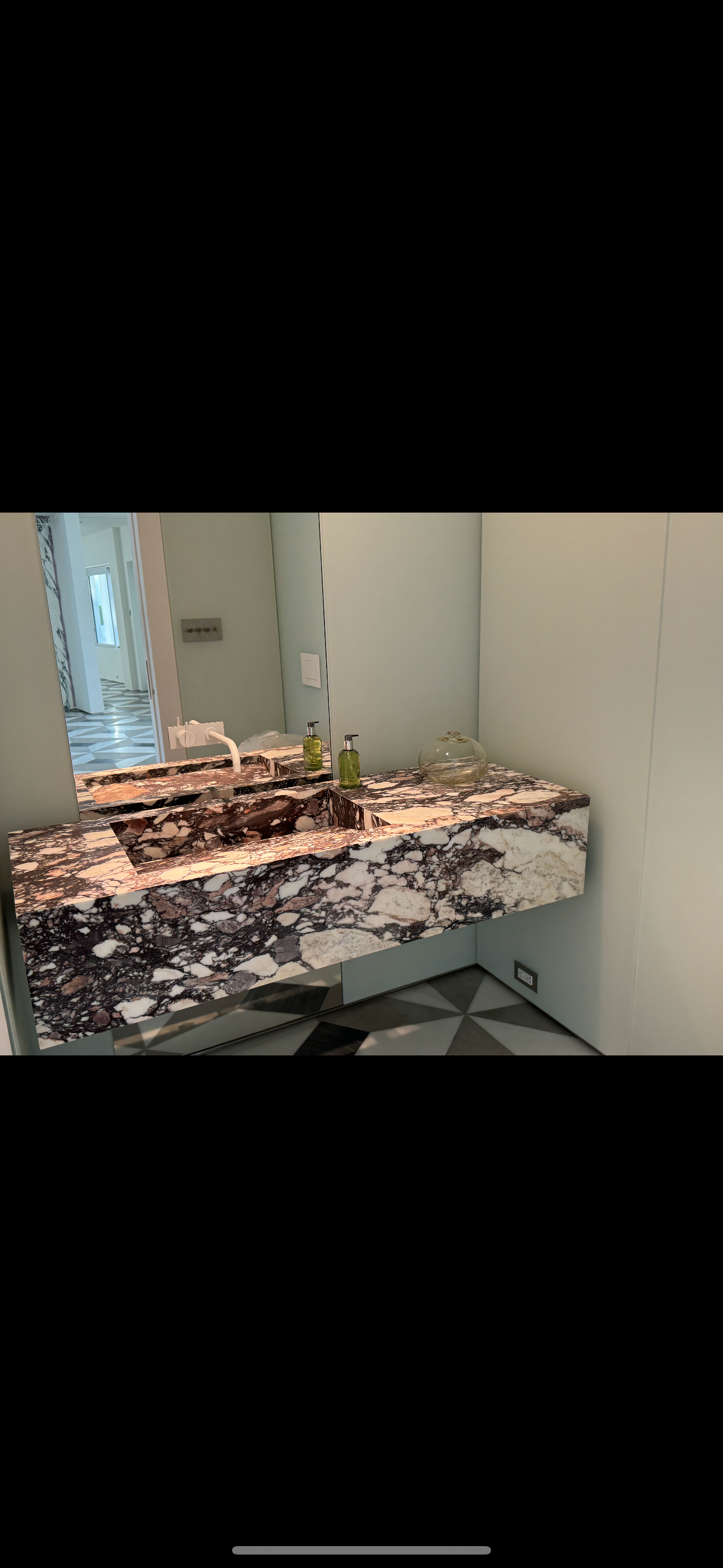 A bathroom with a sink , mirror and marble counter top.