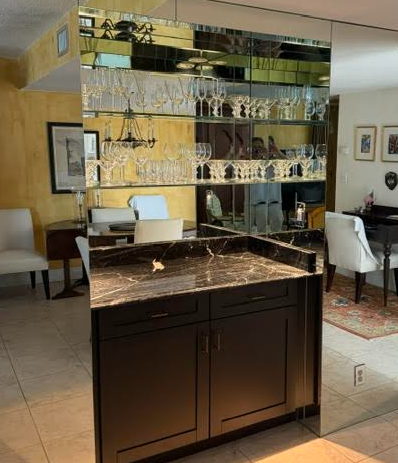 Dark wood bar cabinet with mirrored shelves and glassware in a modern living room