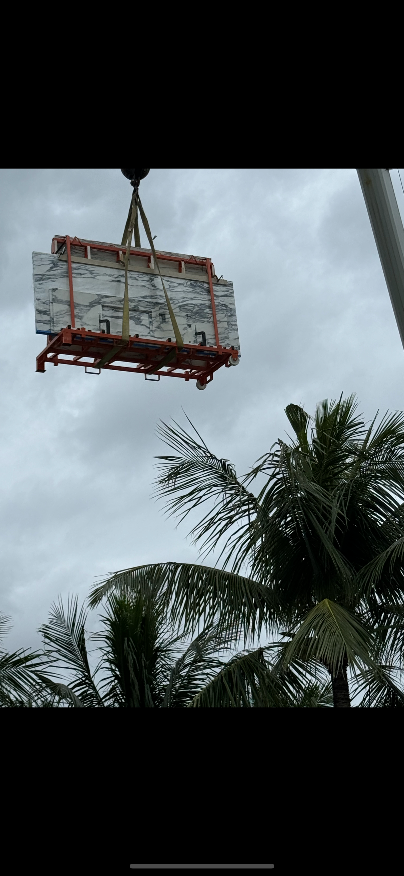 A crane is lifting a large piece of wood in the air.