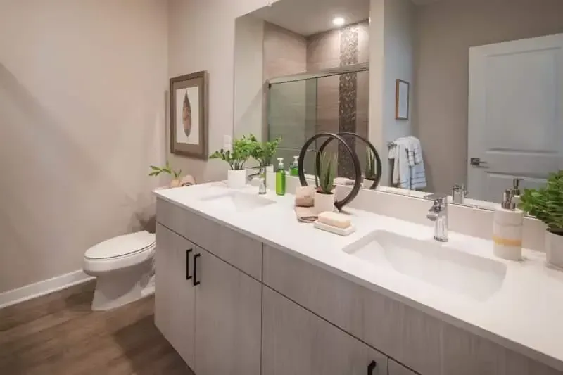 Modern bathroom with double vanity, large mirror, and glass-enclosed shower