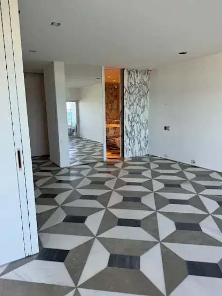 Empty modern room with geometric black, white, and gray tiled floor and white walls
