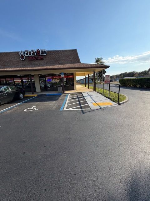Storefront with accessible parking spaces, a ramp, and a handicapped parking sign under a clear sky
