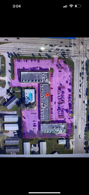 Aerial view of a purple-highlighted rooftop parking lot with a central pool and surrounding buildings.