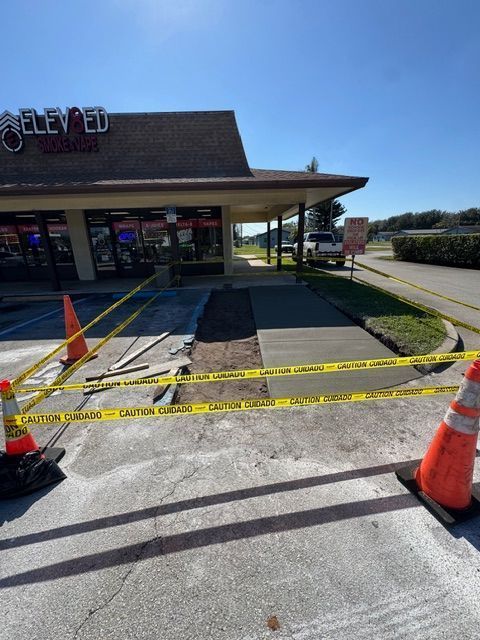 Yellow caution tape blocks a storefront entrance, with orange cones and a closed handicap ramp under bright sun.