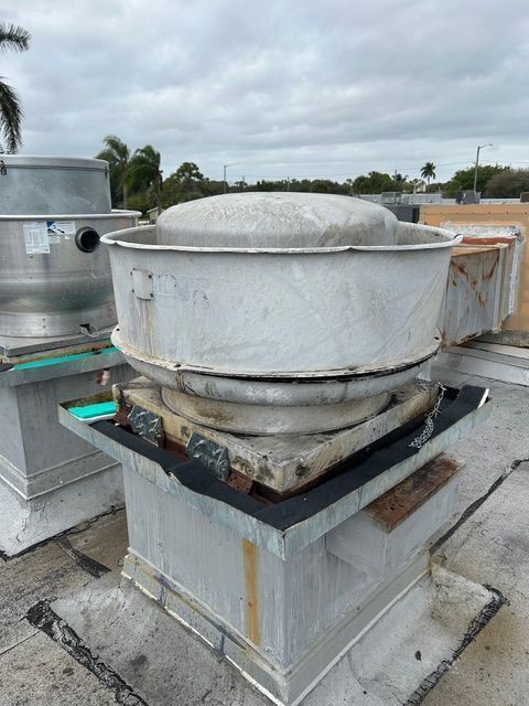 Damaged rooftop HVAC unit with a tilted white metal housing and rusted base on a flat roof