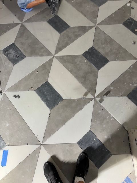 Patterned gray-and-white tiled floor with shoes visible at the bottom edge