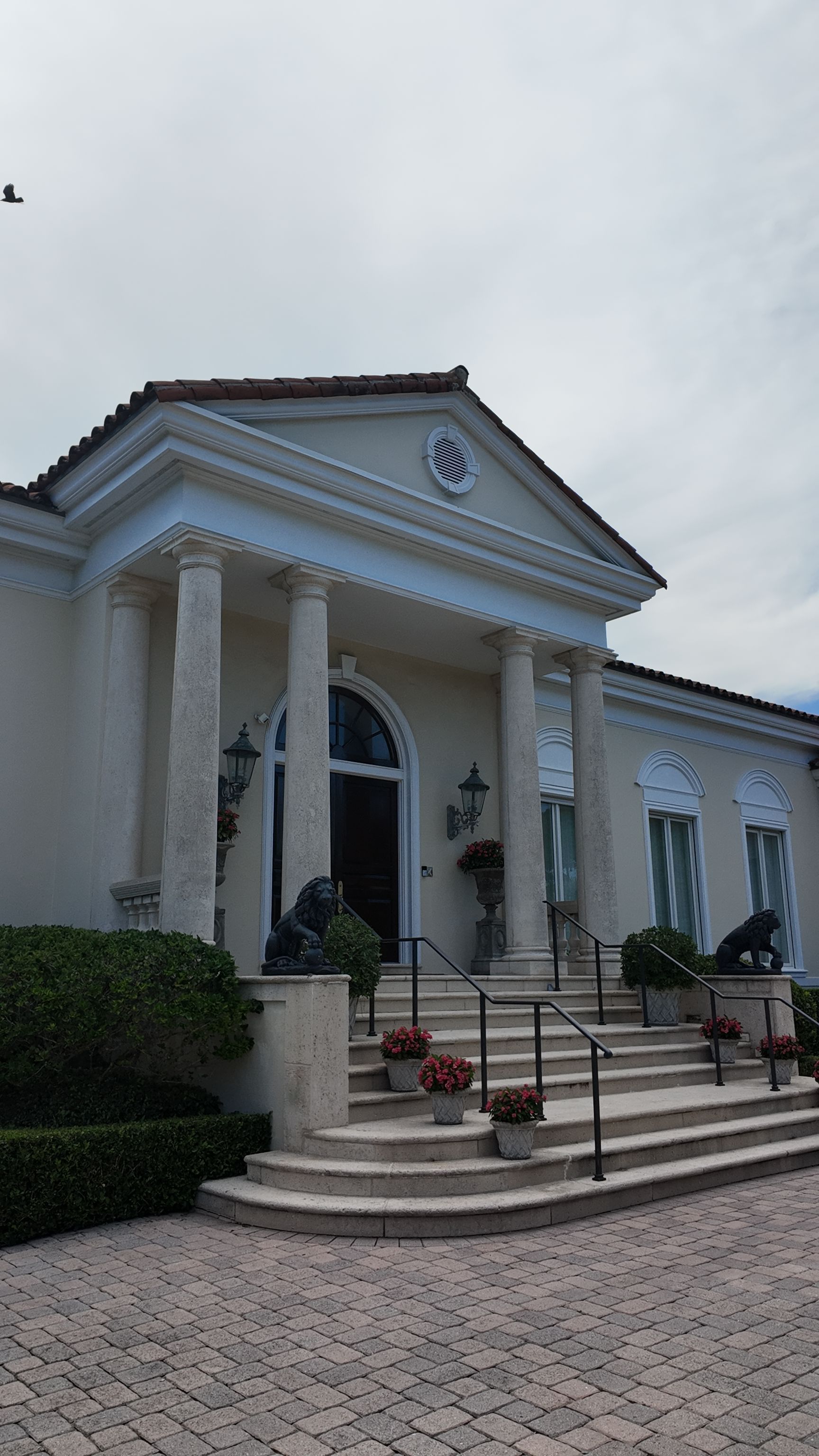White neoclassical building with columns and steps under a cloudy sky