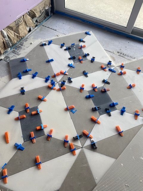 Cloth mat with many blue and orange clips arranged in a starburst pattern on a tiled floor
