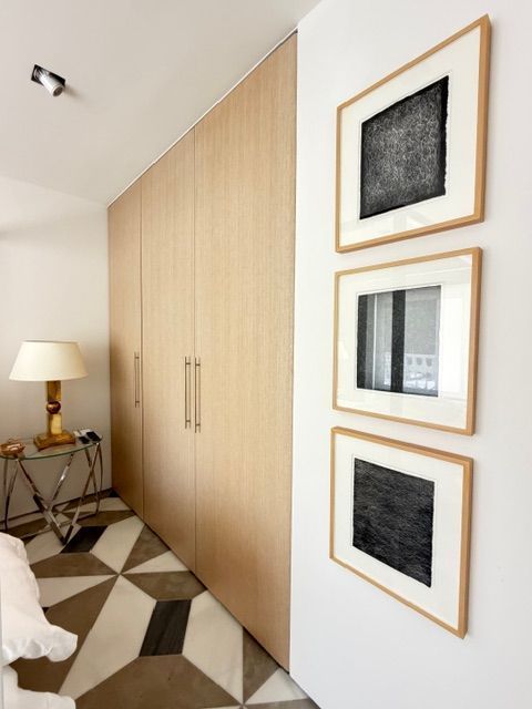 Bright hallway with built-in wood closet, geometric floor, and three framed black-and-white artworks on the wall