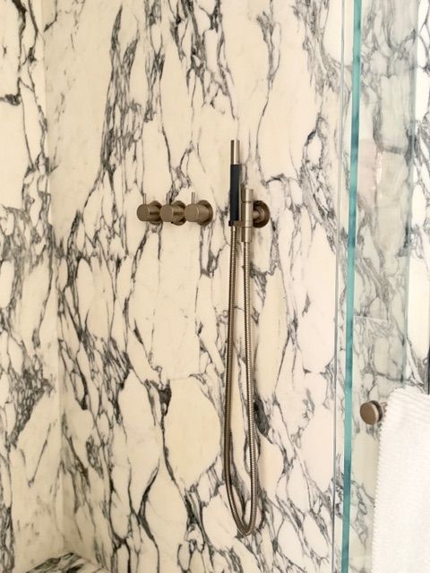 Marble-patterned shower door with metal latch and blue-tinted glass edge