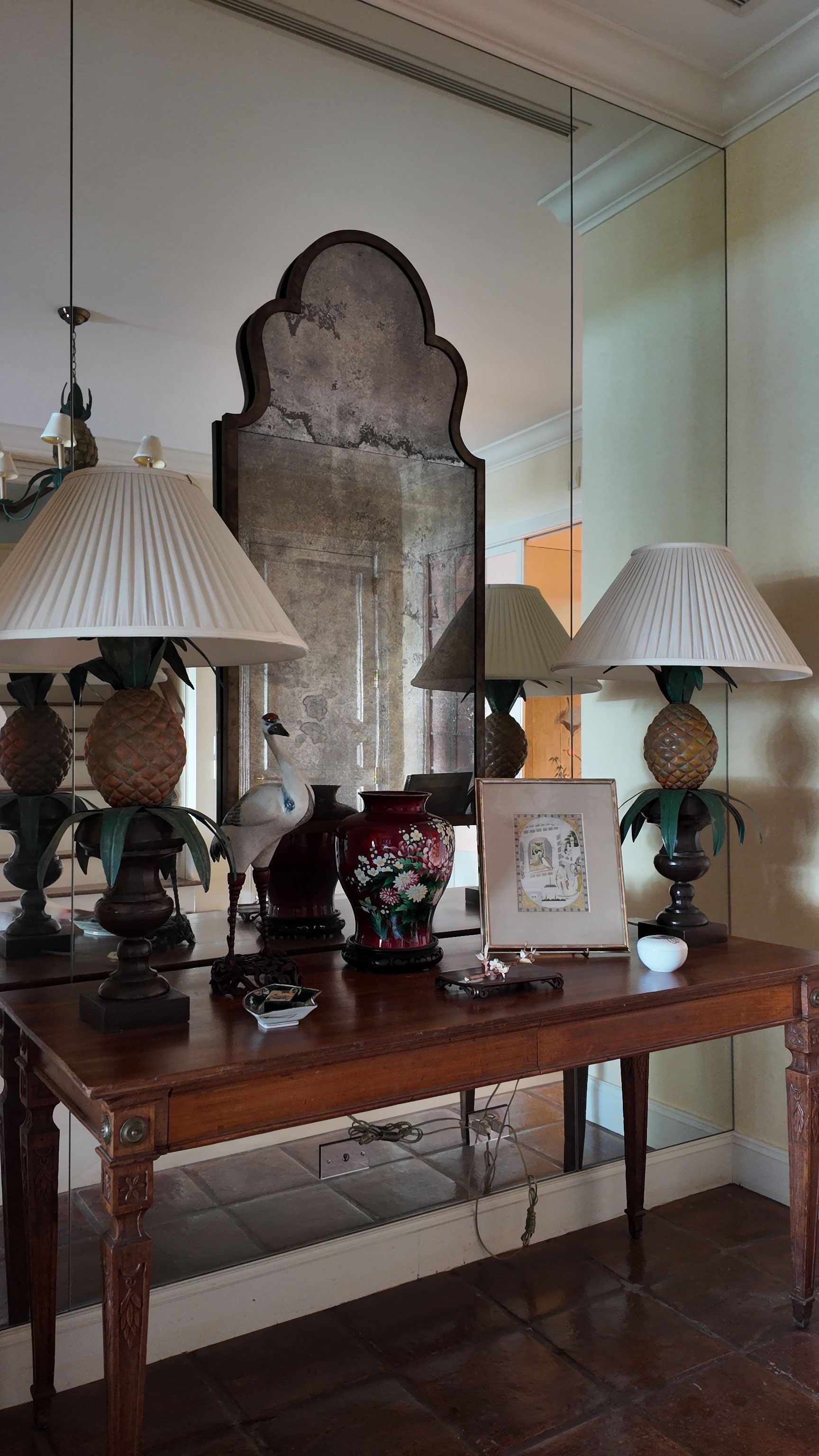 Ornate console table with lamps, mirror, and framed photo in a bright room