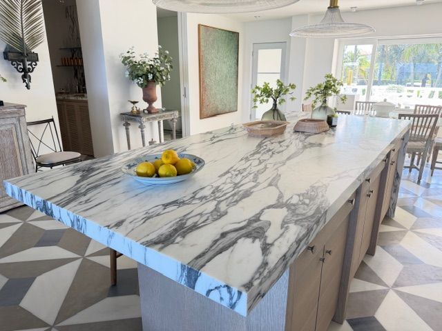 Modern kitchen with a large marble island, fruit bowl, and patterned geometric floor