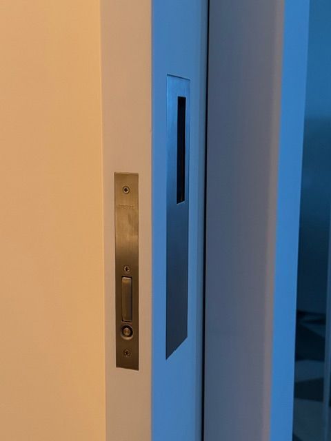 Blue doorway with a narrow glass panel and a brass wall plate beside it