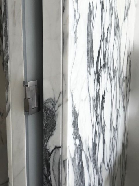 Gray marble wall with a metal door latch or handle in close-up.