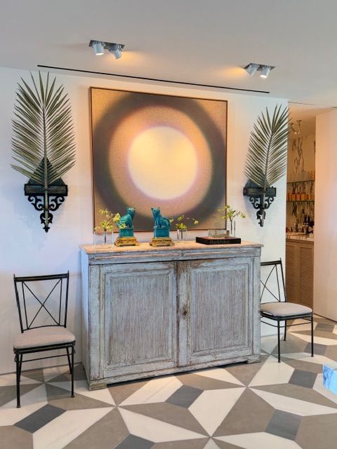 Hallway console table with abstract wall art, decorative vases, chairs, and geometric tile floor