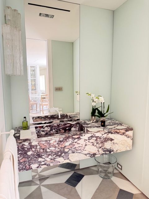 Modern vanity with marble countertop, mirror, flowers, and geometric tile floor in a minimalist room