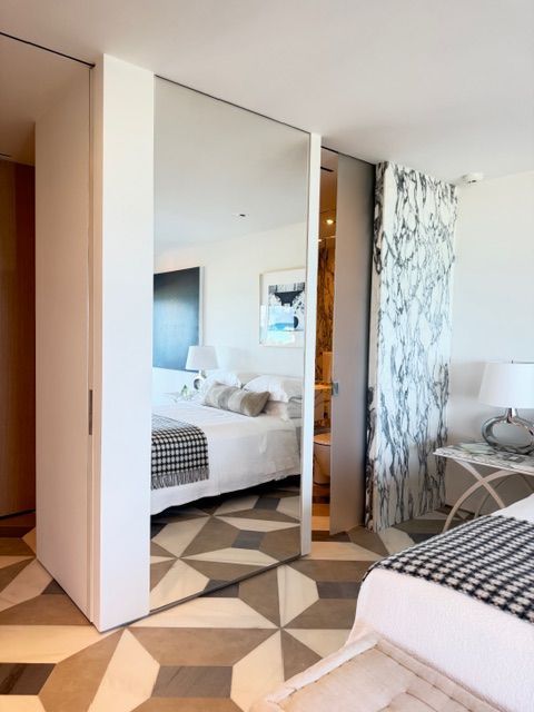 Modern bedroom with mirrored closet doors and geometric tile floor, in neutral tones