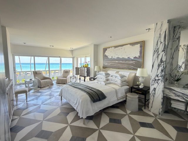 Bright bedroom with ocean view, white furnishings, and geometric gray rug