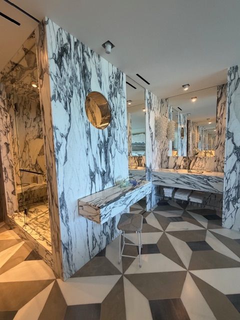 Modern interior with marble-pattern walls, geometric floor tiles, mirrors, and warm lighting.