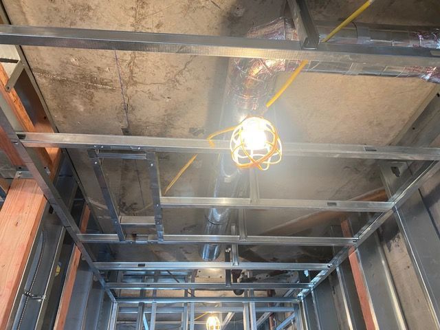 Exposed ceiling framing with a single hanging work light in an unfinished room