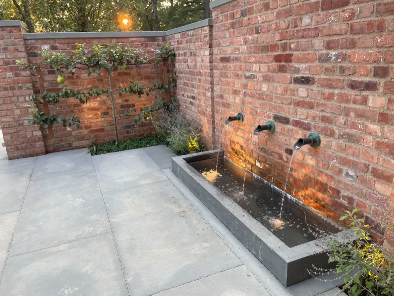 A brick wall with a fountain in front of it
