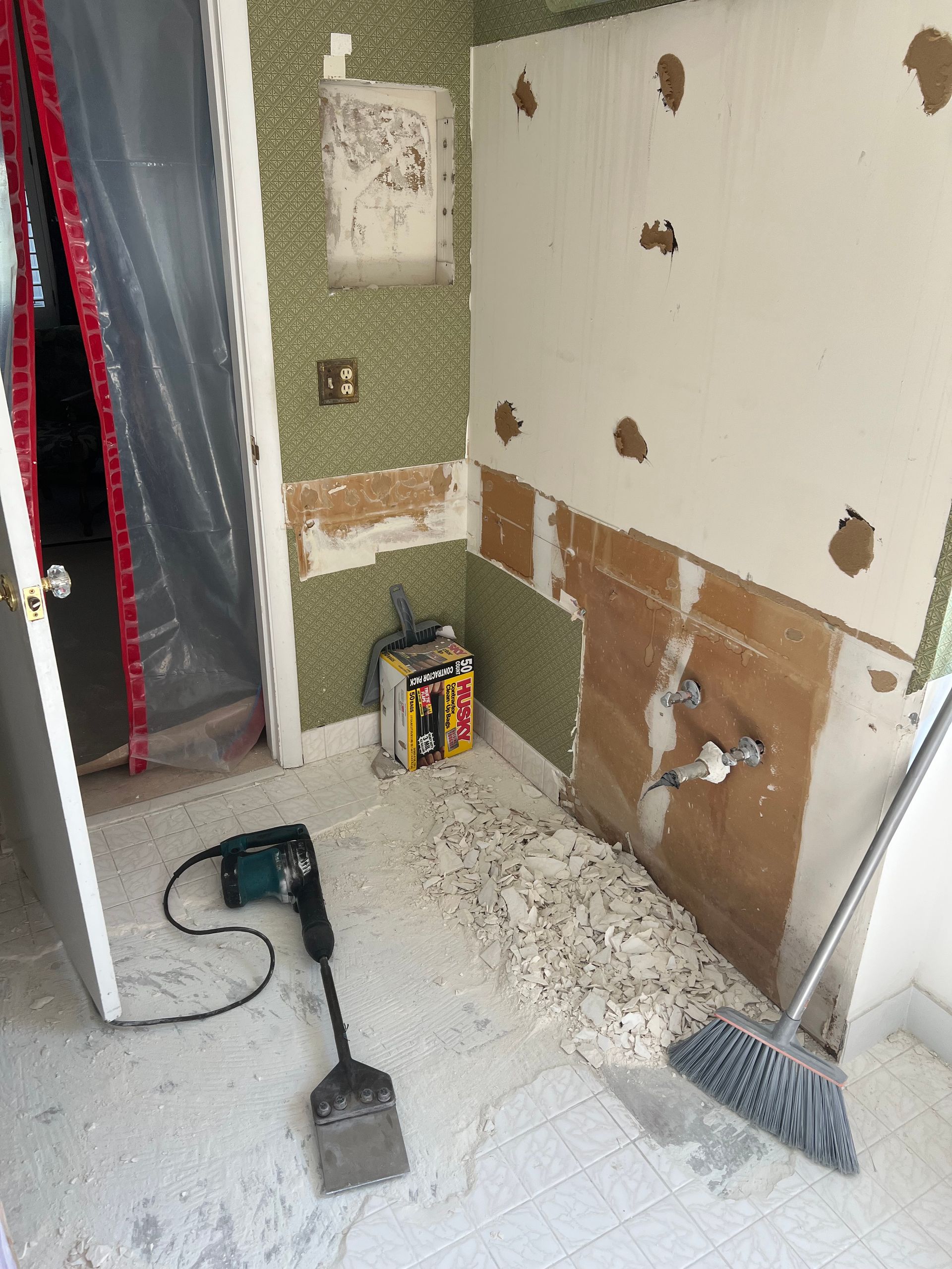 Renovation work in a small room with tools, exposed wall patches, and debris on the floor