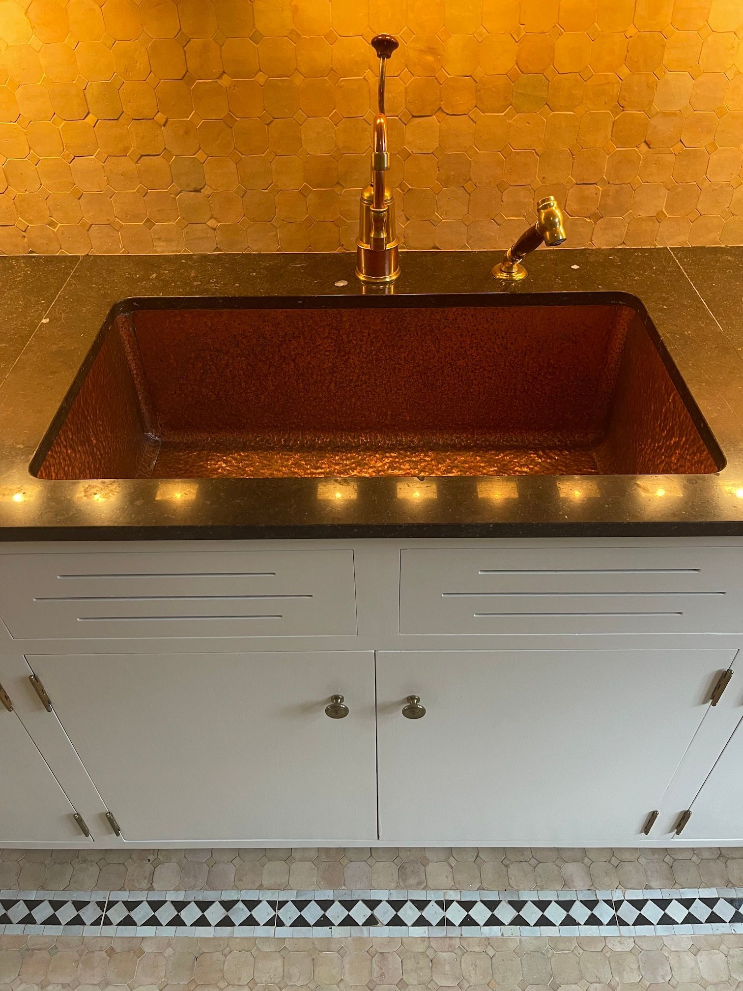 A kitchen sink with a black counter top and white cabinets
