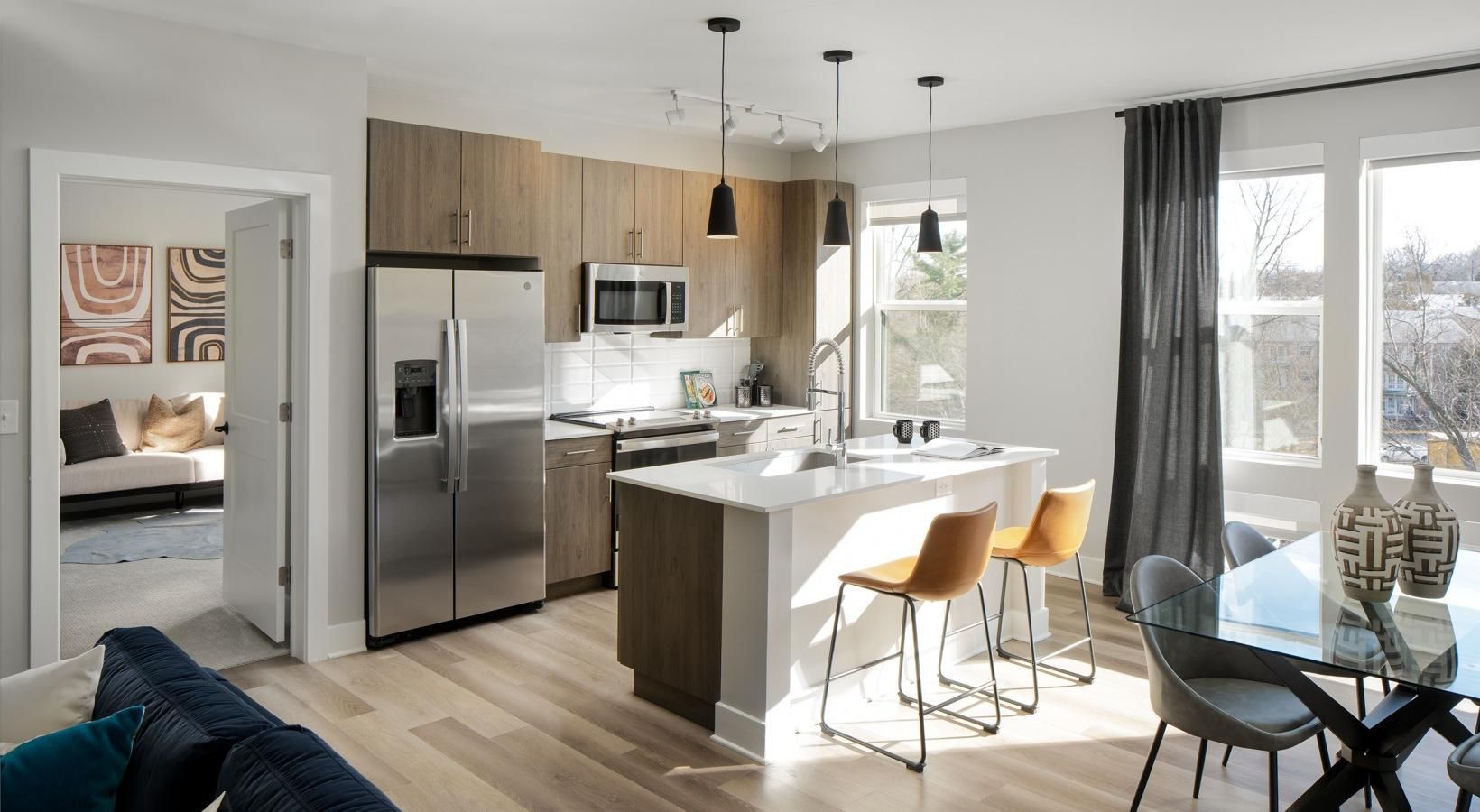 Modern kitchen and dining area with stainless steel appliances, white island, and large windows overlooking a snowy view