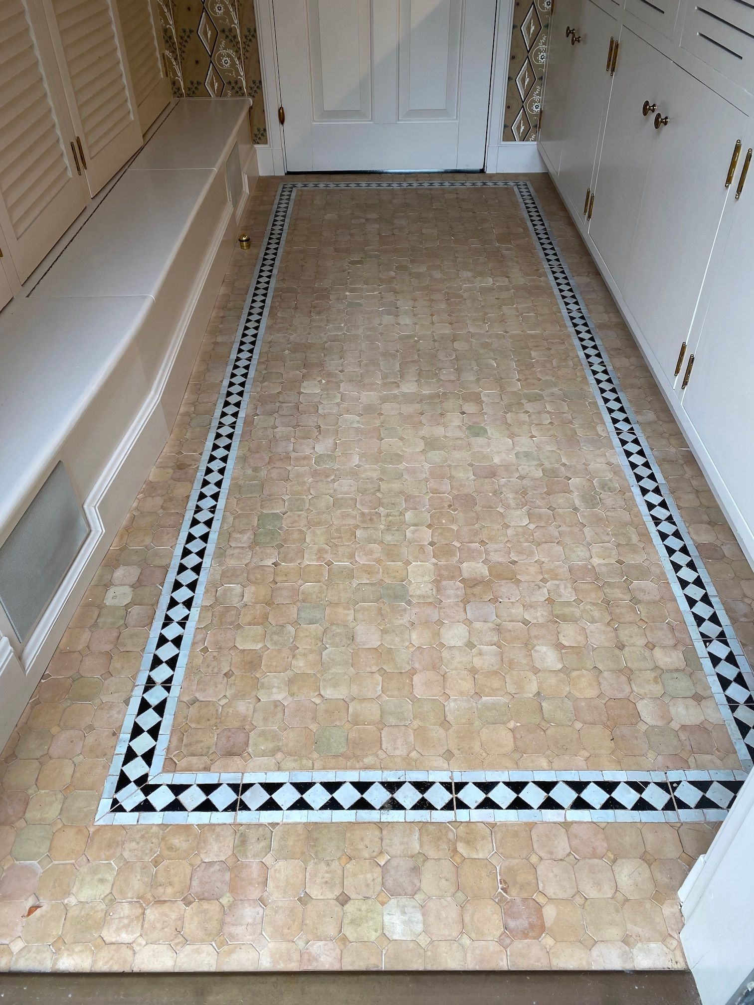 A hallway with a tiled floor and a bench.