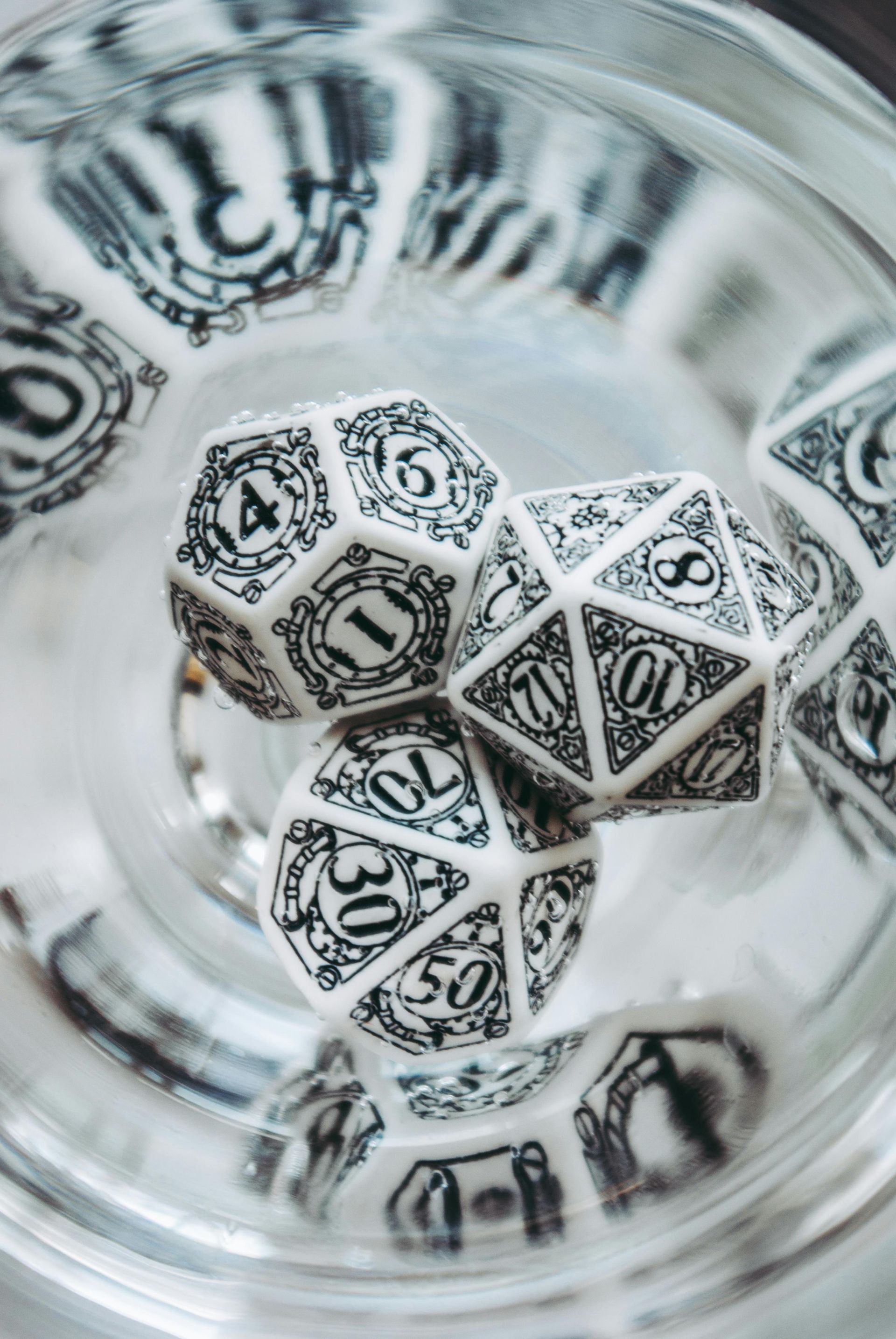 Black-and-white polyhedral dice in a clear glass, viewed from above