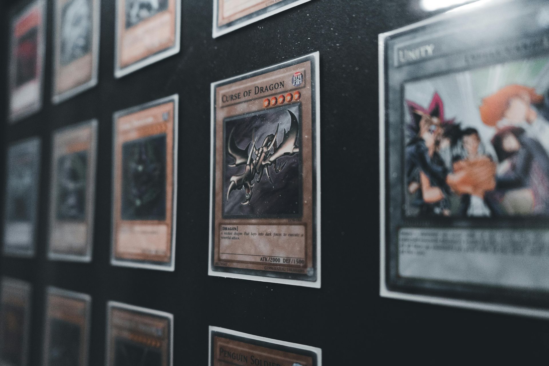 Framed trading cards displayed on a dark wall, with one card in sharp focus