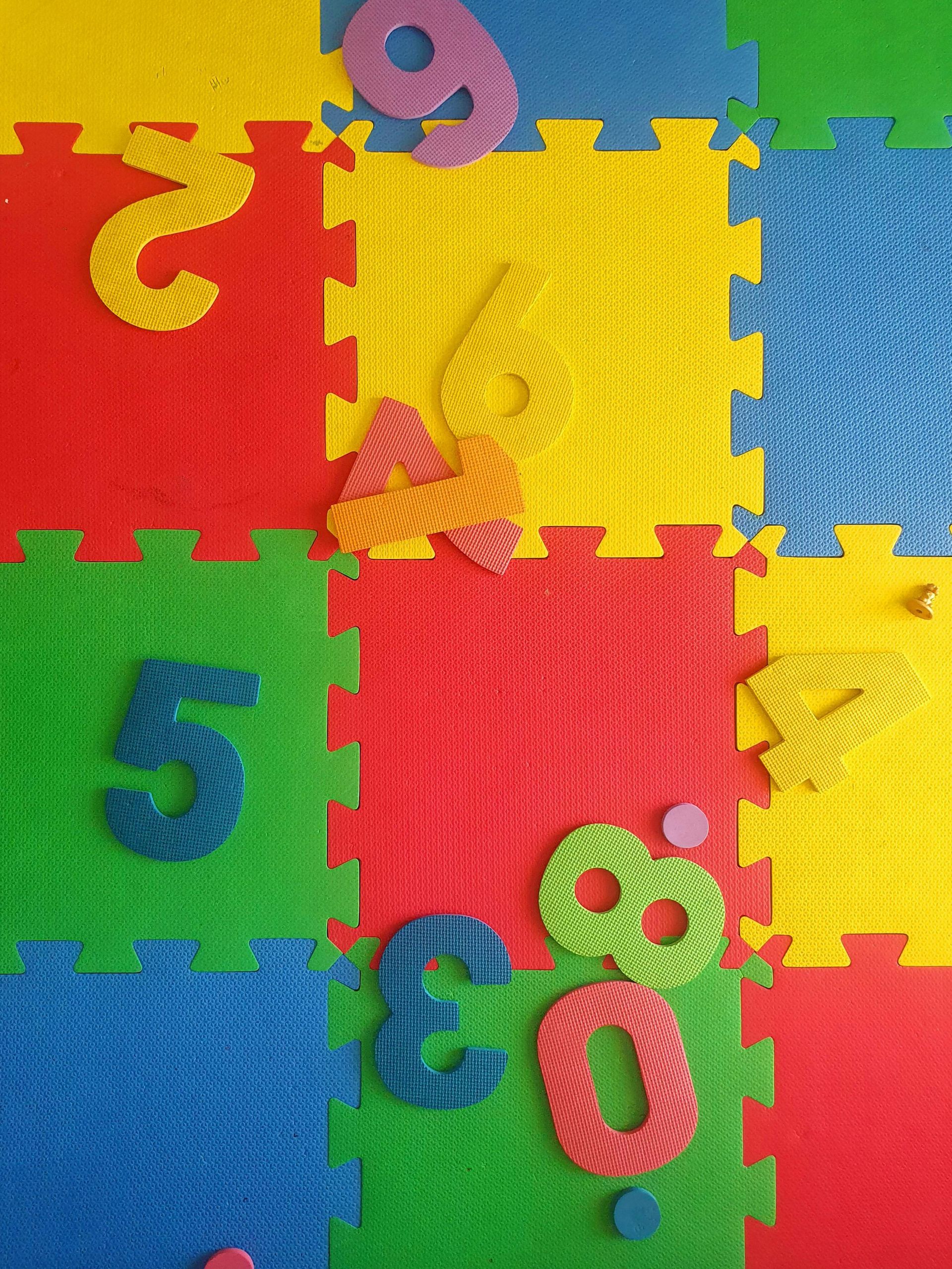 Colorful foam puzzle tiles with scattered number pieces on a play mat