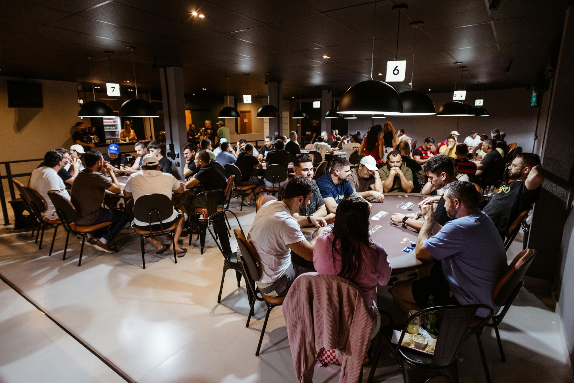 People seated at tables in a dimly lit indoor café or event space, talking and dining