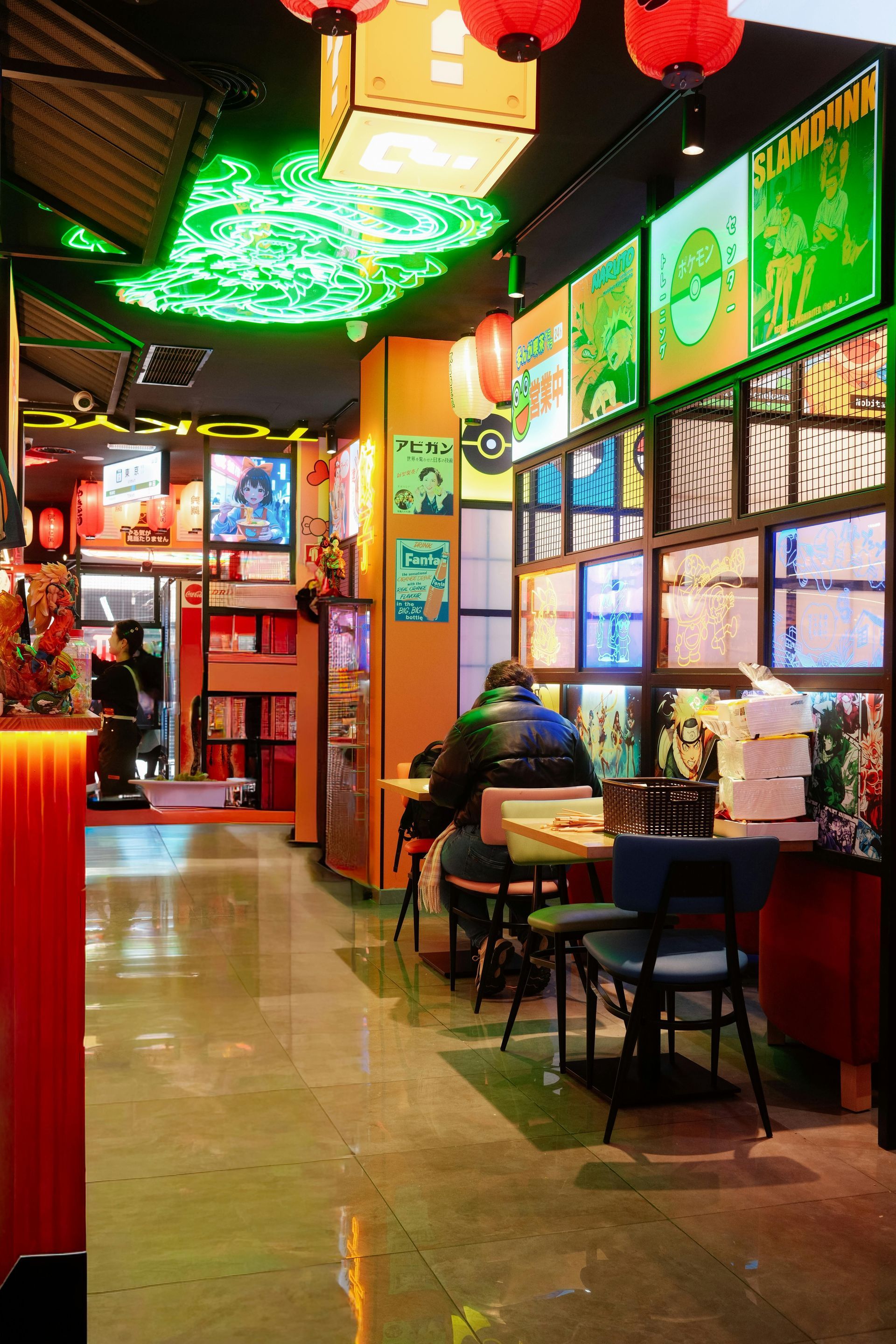 Colorful indoor restaurant with neon lights, red lanterns, and a seated diner by the window.